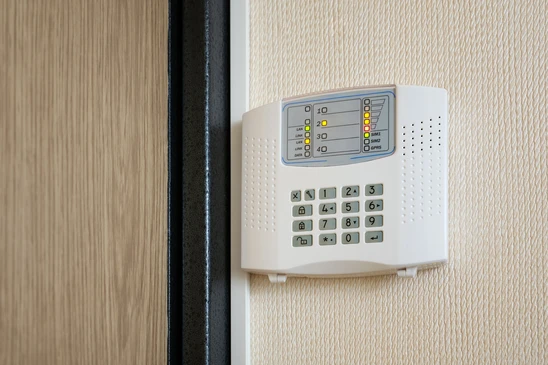Homme installant un système d'alarme de sécurité à la maison sur un mur blanc à l'intérieur, gros plan