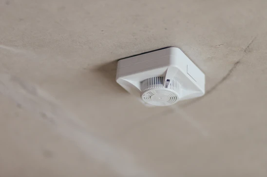 Intérieur d'un bâtiment avec mur blanc où est fixé un déclencheur manuel d'alarme incendie rouge